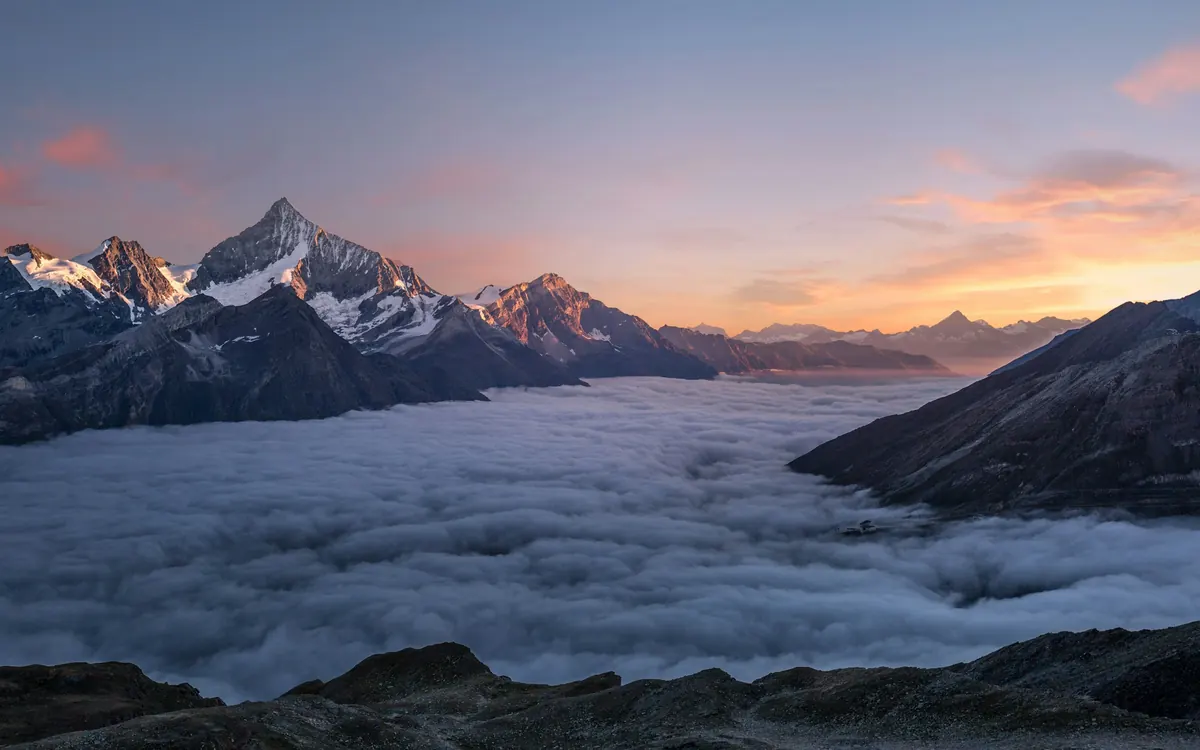 Mountain peaks rising above a sea of cloud at sunrise