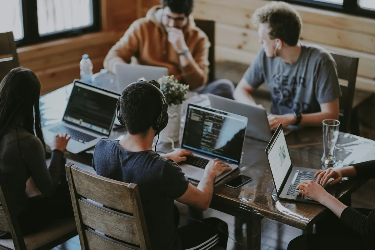 A software team working side by side on laptops around a shared table